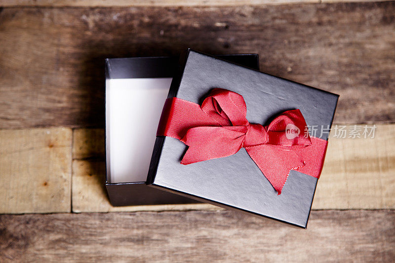 情人节,圣诞节。黑色礼盒，红色丝带。木制的桌子。