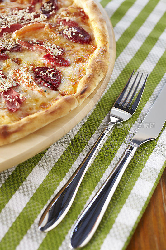 披萨和餐具放在条纹桌布上。