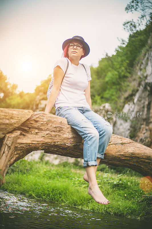 一个女人坐在河上倒下的树干上