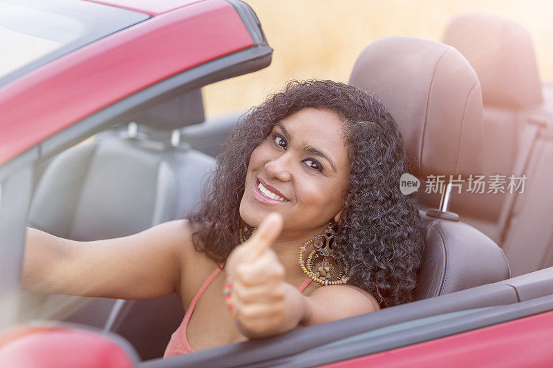 美丽的巴西女人驾驶敞篷车竖起大拇指