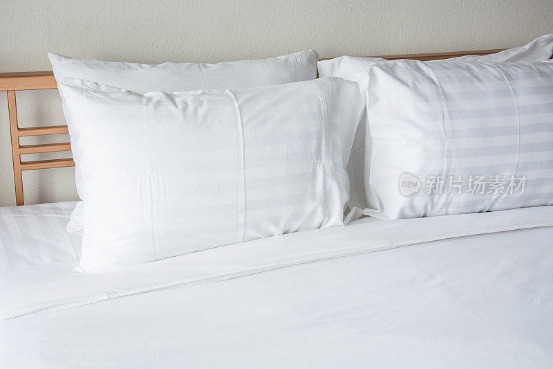床上有白色枕头，卧室里有白色毯子