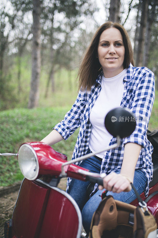 戴着头盔坐在老式摩托车上的年轻时髦女人。