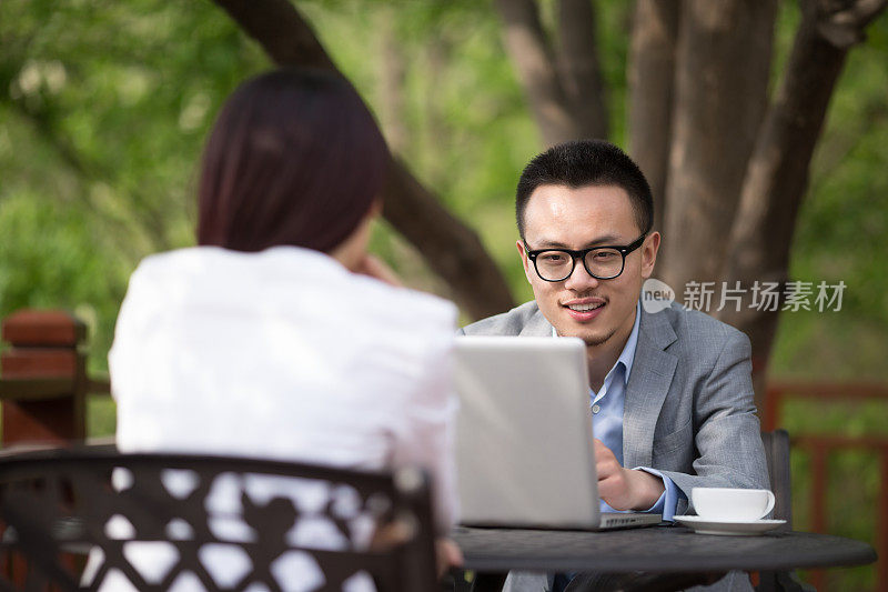 年轻的亚洲商人在户外咖啡馆聊天