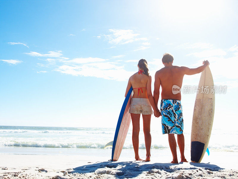 一对在海边玩冲浪板的幸福夫妇