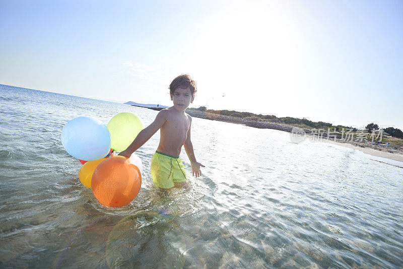 男孩在海里拿着气球