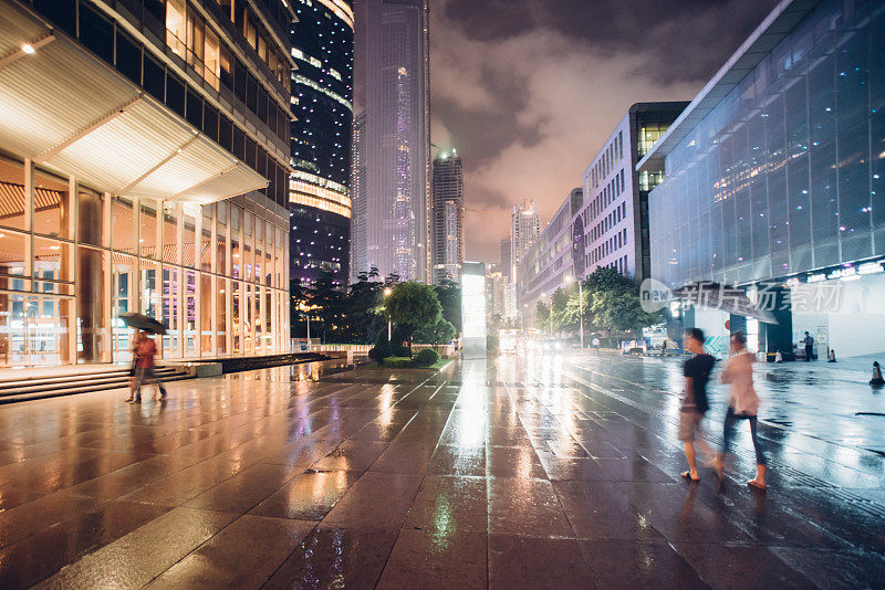 人们在雨中行走，在城市的夜晚