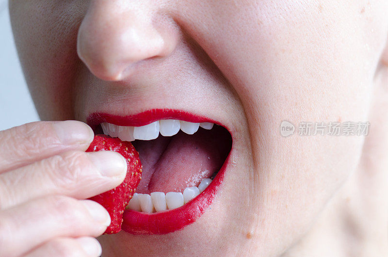 近距离观察把草莓放进嘴里的女人