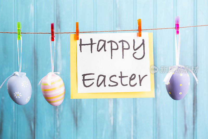 复活节彩蛋的装饰品挂在蓝木头上。季节性的背景框架。