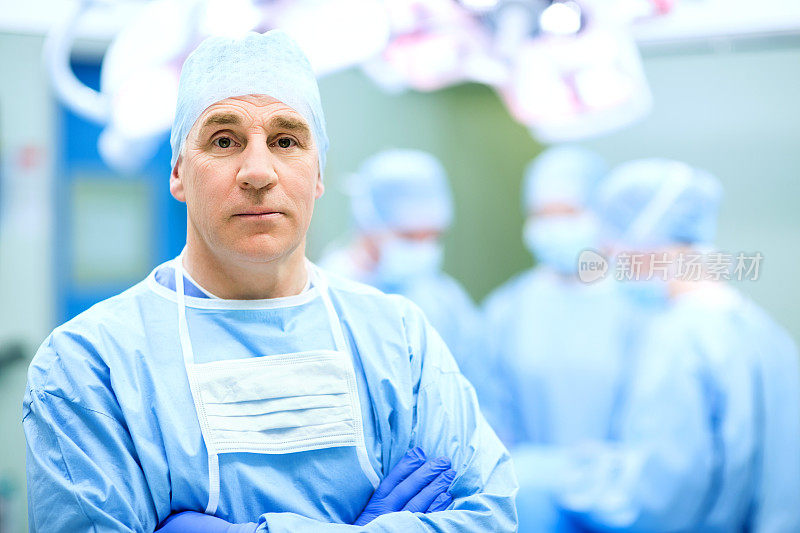 成熟的男性外科医生双臂交叉站在手术室里