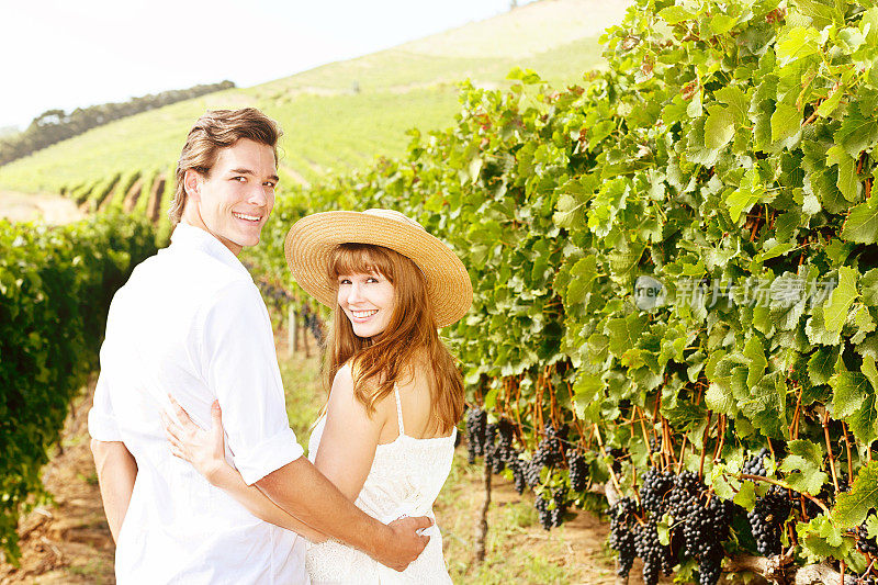一对夫妇走过美丽的葡萄园，转过身微笑着