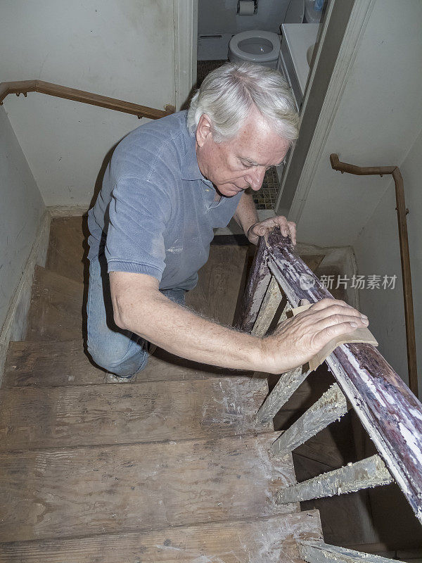 房屋装修——高级男子用手打磨楼梯栏杆