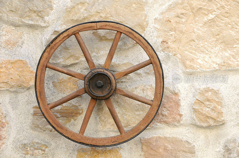 旧的修复干净的马车车轮在石墙上靠近