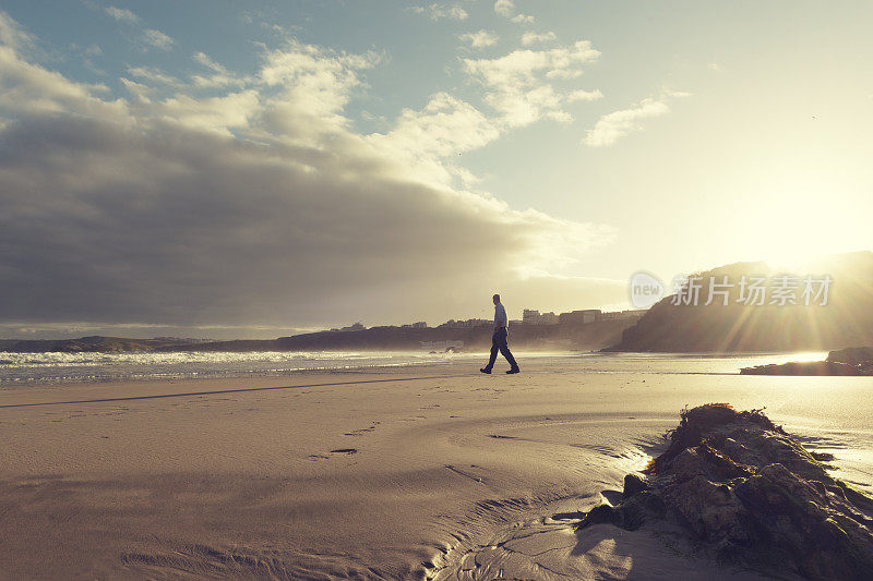 日出时分，沿着海滩散步的人