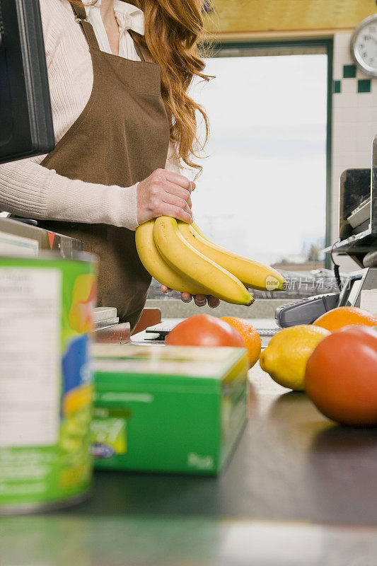 超市收银员在收银台为香蕉定价