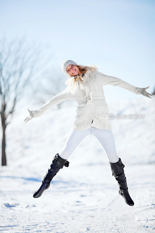 女人在冬天被雪包围着跳跃