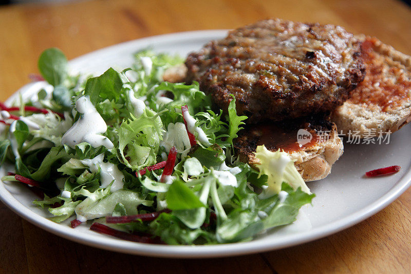 自制牛肉汉堡配烤面包卷和蔬菜沙拉