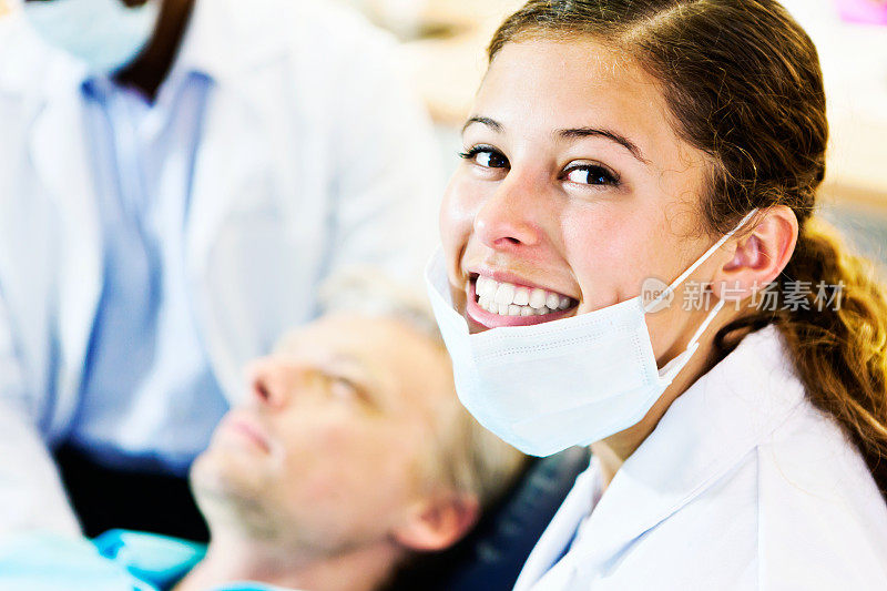 牙科助理转向镜头从病人和微笑