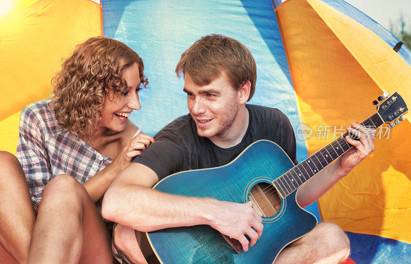 露营:一对在帐篷里拿着吉他的夫妇