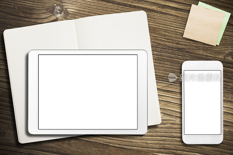 数字平板电脑与便利贴和笔记本在旧木头上。