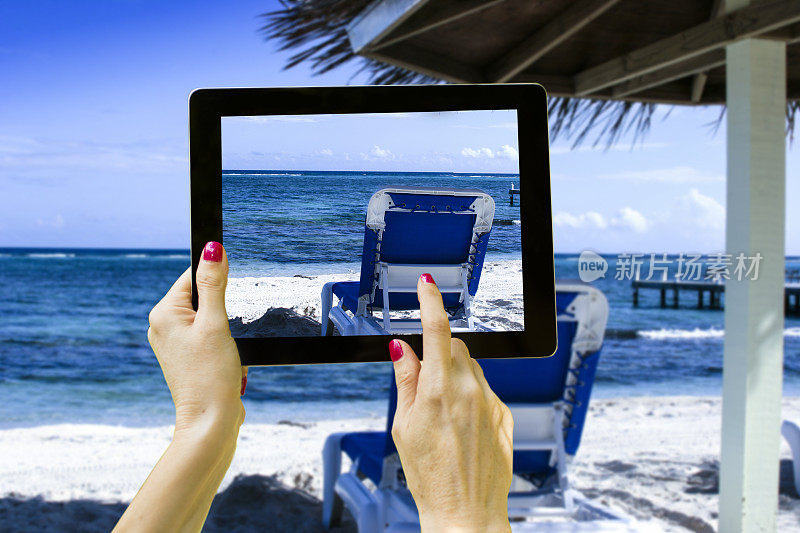女子用平板电脑拍照海滩度假,技术。