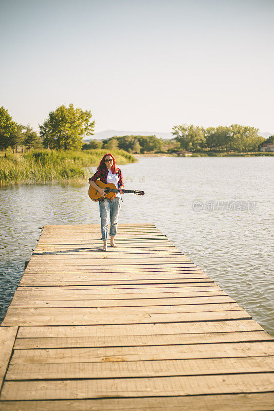 年轻女子在码头上弹吉他