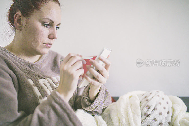 睡在床上的女人穿着睡衣看手机