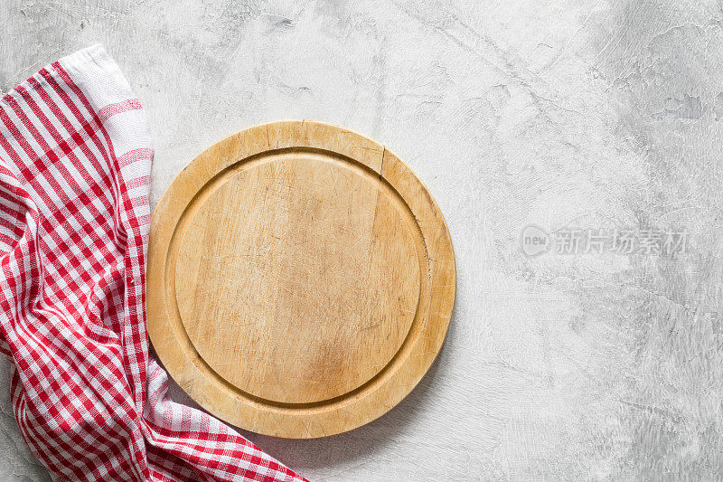 旧的圆形木砧板或比萨饼板和红色格子纺织品