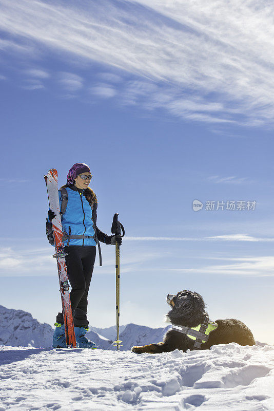 狗在山上的雪地里与女主人一起滑雪