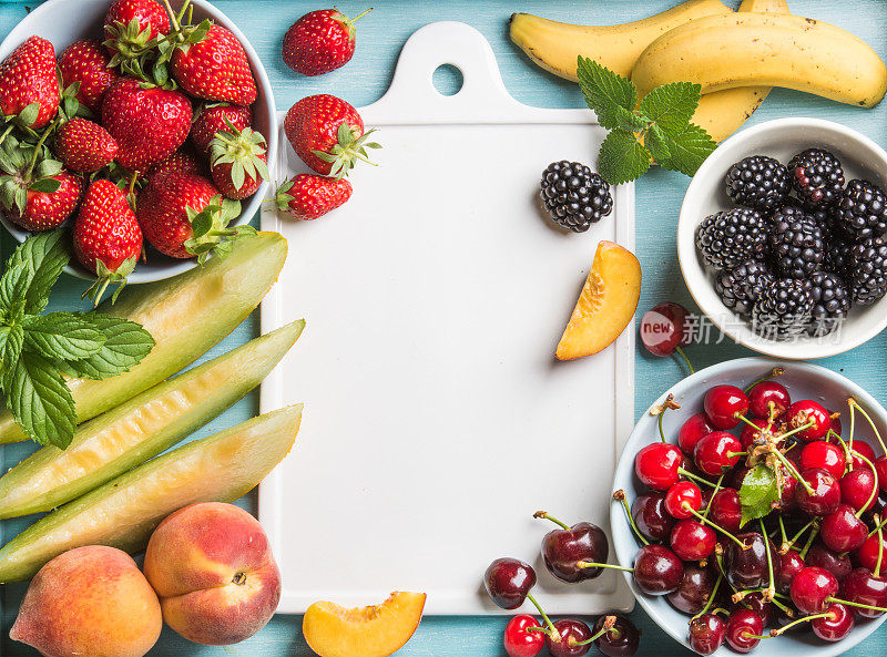 健康的夏季水果品种。甜美的樱桃，草莓，黑莓，桃子，香蕉，甜瓜片和薄荷叶在蓝色的背景与白色陶瓷板在中心