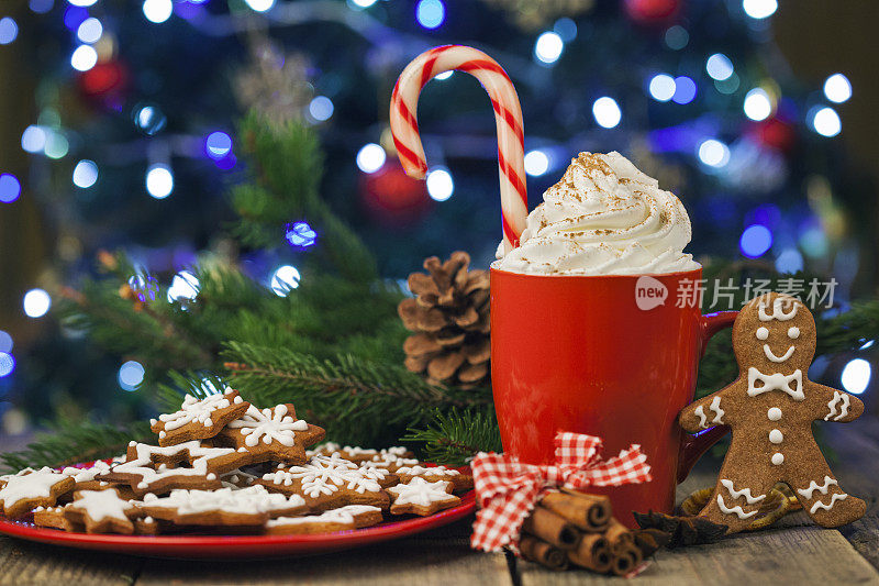 圣诞卡布奇诺和姜饼饼干在圣诞树前，在乡村木桌上