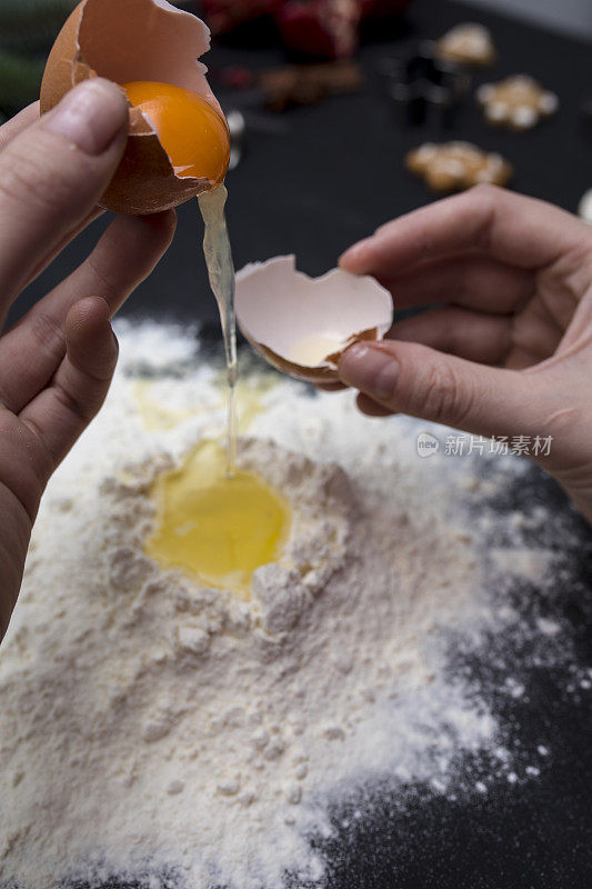 女性面包师的手打碎鸡蛋成生面团的特写。烘焙和食品准备的概念。