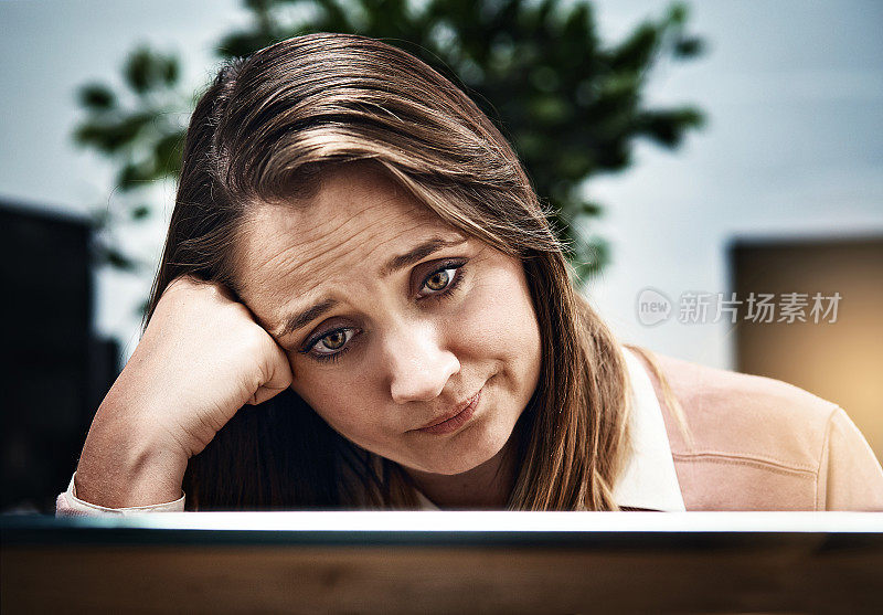 愁眉苦脸的女工对着电脑显示器，头在手上