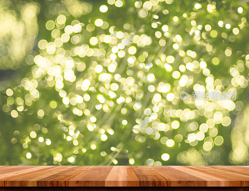 空的棕色木材桌面与模糊的圣诞灯装饰在绿树虚化的背景，模板模拟蒙太奇的产品