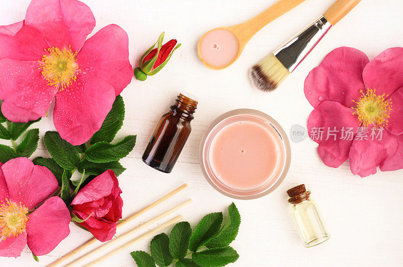 粉红色的新鲜野生玫瑰花和叶子，瓶子和罐子，俯视图。