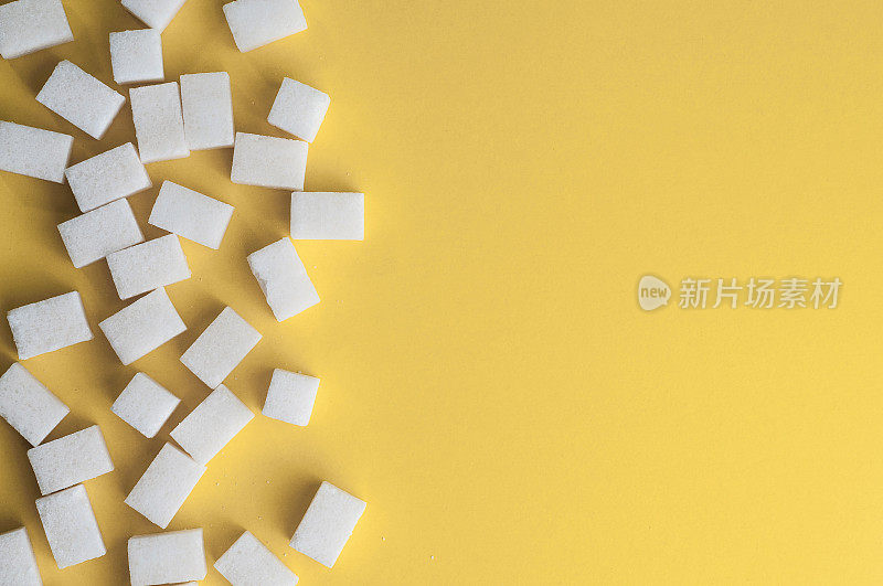 黄色背景上的白糖。方糖与复制空间。俯视图或平铺