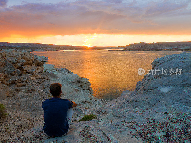 在美国犹他州瓦赫韦普湾鲍威尔湖看日落的年轻人