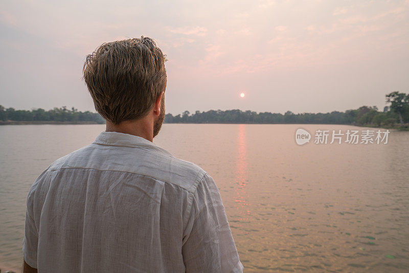 一个年轻人在柬埔寨的湖边凝视夕阳