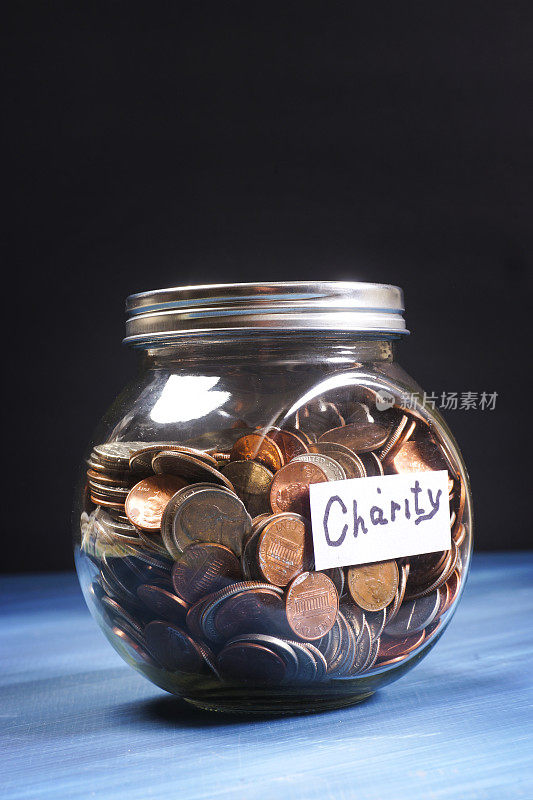 玻璃罐子装满了标有慈善的硬币