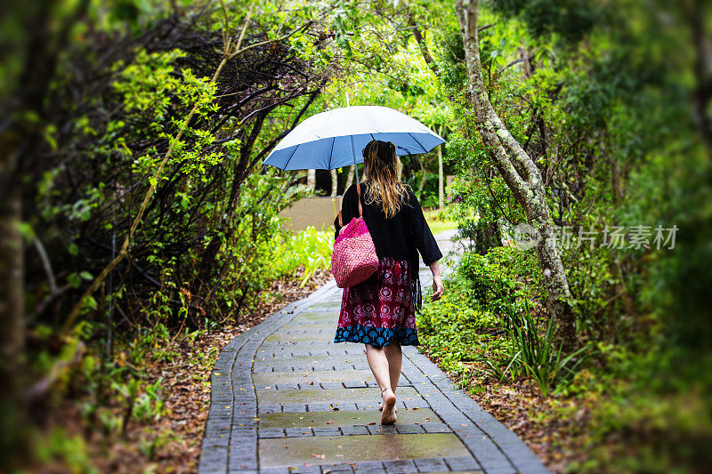 雨中，一个女人独自走在一条砖路上