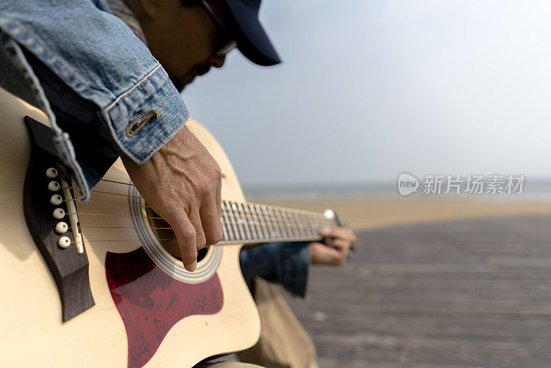 在海滩上弹吉他的男人