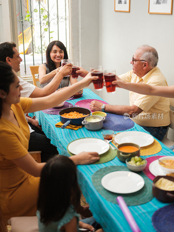欢乐的墨西哥家庭围坐在桌旁互相敬酒