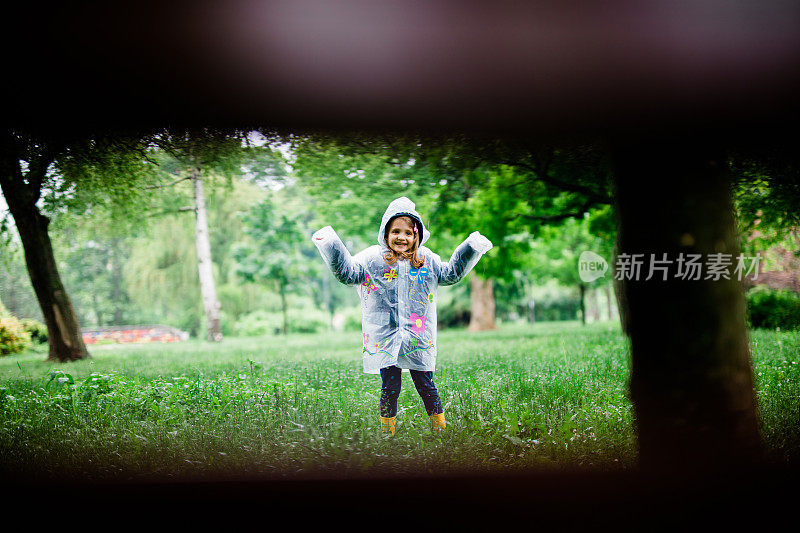 小女孩在城市公园的雨中奔跑。