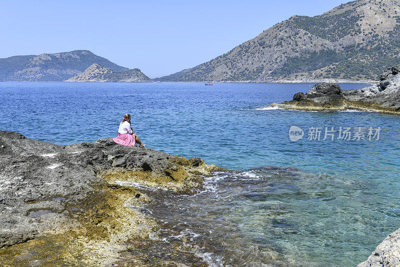 在岩石顶端的女人望着大海。