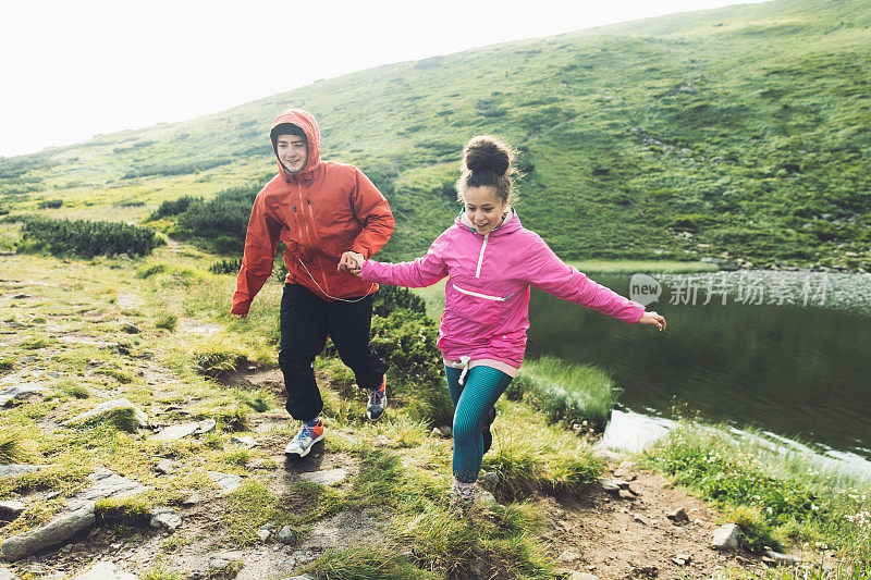 年轻夫妇在美丽的湖附近的山上玩耍