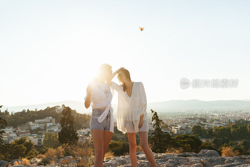 两名女游客在雅典的山上欣赏日落