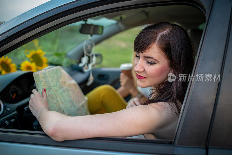 年轻女子正在开车，一边看地图。