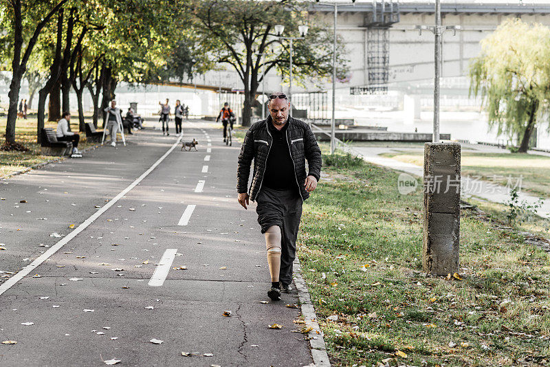一个戴着假肢的成年人正在城市公园里散步