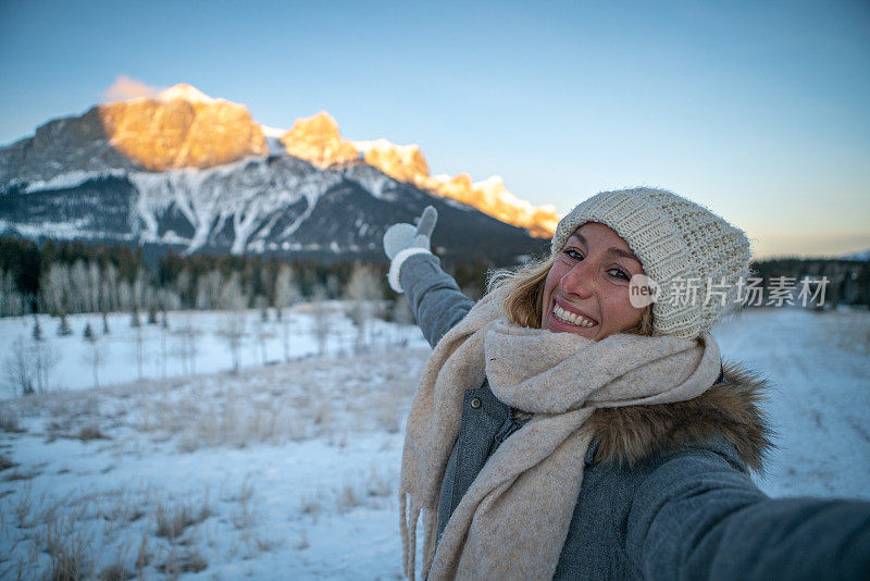 年轻女子在冬天与雪山景观自拍;人们在寒假里玩得很开心