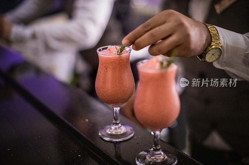 一个调酒师在做最后的润色，用新鲜的百里香装饰草莓代基里酒。