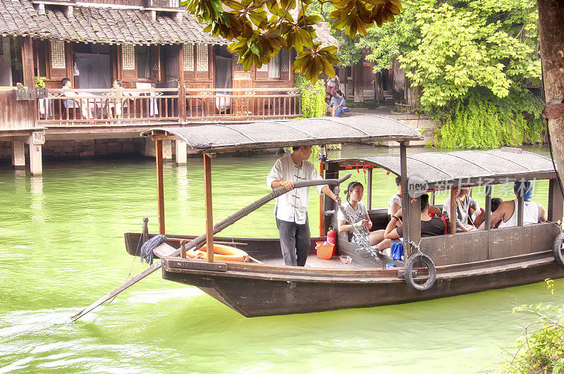 游客在中国乌镇的水渠上游船